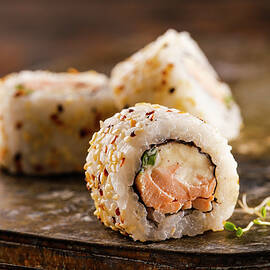 Sushi Roll With Salmon, Cream Cheese And Green Onion Covered With Sesame Seeds by Yumpic Studio