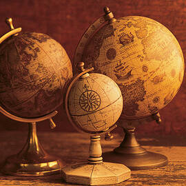 Three Globes With World Map Backdrop by Comstock