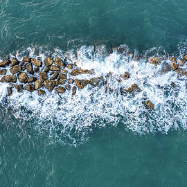 Aerial view from a flying drone of blue sea water and break water. Sea wall coastline by Michalakis Ppalis