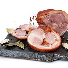 Appetizing smoked pork shank sliced , on a charred chopping boar by Dorin Puha