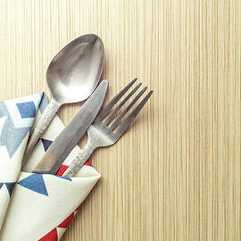 Dinner table backdrop with spoon fork and knife in a patterned f by Dorin Puha