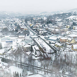 Drone shot of a small town named Limanowa in mountains in Poland covered with fog and snow by Arpan Bhatia