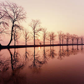 Endlessness - Silhouette reflected on an early morning sunrise by Roeselien Raimond