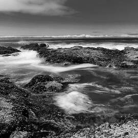 Raging waves assailing the rocks black and white by Jeff Swan