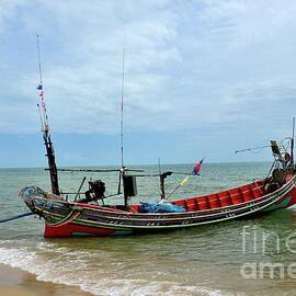 Sea going fishing vessel boat with outboard motor parked on beach in Pattani village Thailand by Imran Ahmed