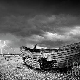 Stormy Dungeness, Wrecked boat on a shingle beach with lightning by Neale And Judith Clark