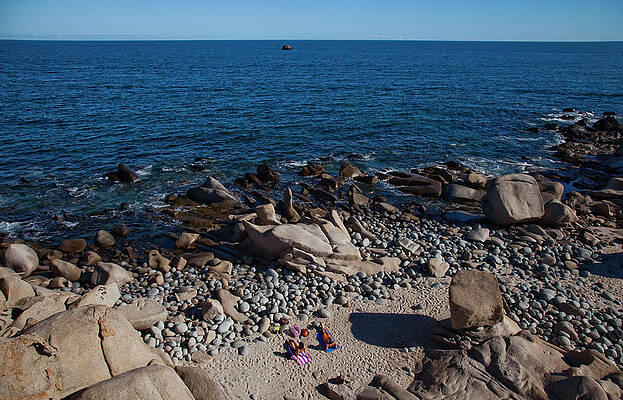 Wall Art - Photograph - A Couple Enjoy An Empty, Rocky Beach by Michael Hanson
