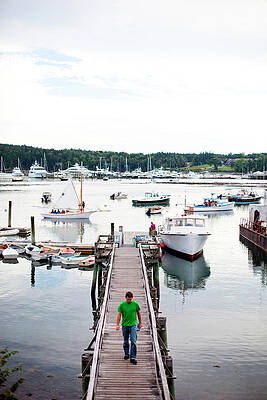 Wall Art - Photograph - A Man Walks On A Dock In A Harbor by Michael Hanson