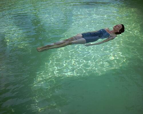 Wall Art - Photograph - A Model Floating In A Swimming Pool by John Rawlings
