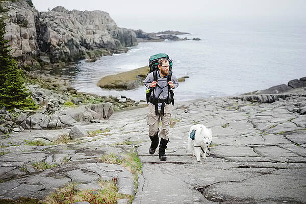 Wall Art - Photograph - Man Backpacking With Dog Along Atlantic by The Open Road Images
