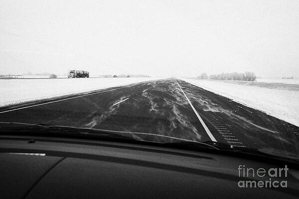 Wall Art - Photograph - snow blowing over road while winter driving along Saskatchewan highway 11 from Saskatoon to Regina C by Joe Fox