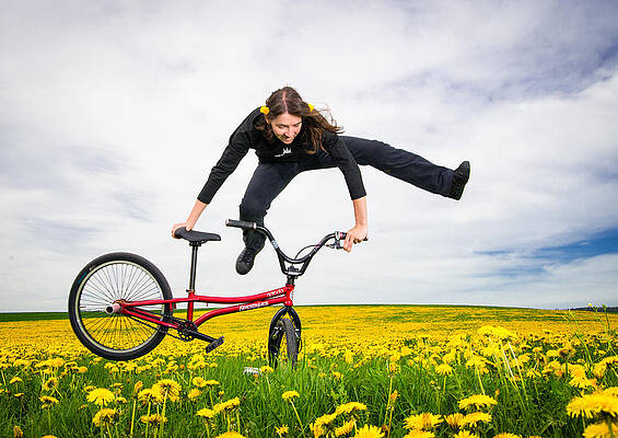 Wall Art - Photograph - Spring has sprung - BMX Flatland artist Monika Hinz jumping in yellow flower meadow by Matthias Hauser