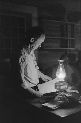 Wall Art - Photograph - Man Reading By The Light Of A Kerosene by Everett