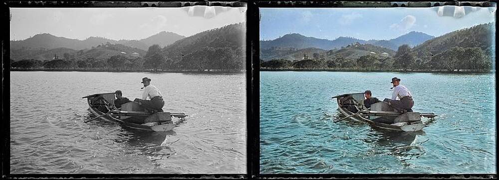 Two Men Crossing Lake In Row Boat Laden With Heavy Boxes To Shore