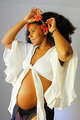 Wall Art - Photograph - A Beautiful Young Pregnant Woman Places Flowers In Hair by Cavan Images / Rebecca Tien