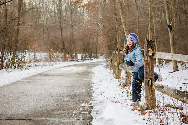 Wall Art - Photograph - A Little Girl Sits On Wood Fence Along Snowy Fence With Binoculars by Cavan Images / Rebecca Tien