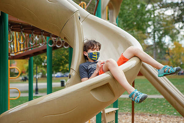 Wall Art - Photograph - A Masked Boy With Direct Gaze Sits In The Middle Of A Slide by Cavan Images / Rebecca Tien