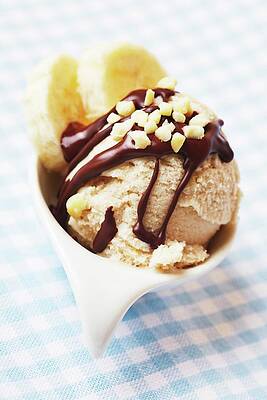 Wall Art - Photograph - A Mini Banana Split With Banana Ice Cream, Slices Of Banana, Chocolate Sauce And Nut Brittle by Robert Kneschke