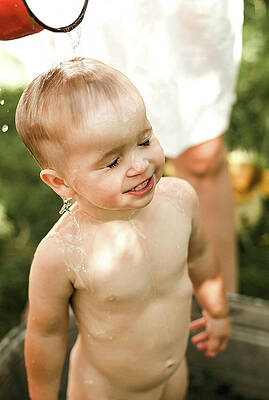 Wall Art - Photograph - A Mother Rinses Her Son's Hair While Bathing Her In The Backyard by Cavan Images