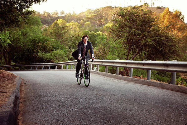 Wall Art - Photograph - Businessman Riding Bicycle On Road by Cavan Images