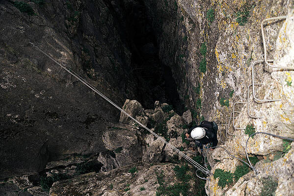 Wall Art - Photograph - Concept: Adventure. Climber Man With Helmet And Harness. Aerial View Of The Abyss In The Rock. Climbing To The Top Of The Mountain. Via Ferrata On Rock. by Cavan Images