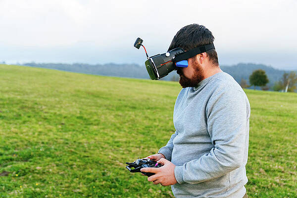 Wall Art - Photograph - Man Using A Drone With Remote Controller Wearing Vr by Cavan Images