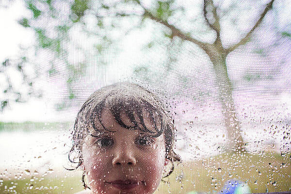Wall Art - Photograph - Portrait Of Boy Seen Through Wet Metal Grate by Cavan Images