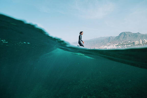 Wall Art - Photograph - Pulled Back Split Image Of Female Surfer In Wetsuit On A Wave by Cavan Images