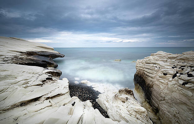 Wall Art - Photograph - Rocky coast with white limestones and cloudy sky by Michalakis Ppalis