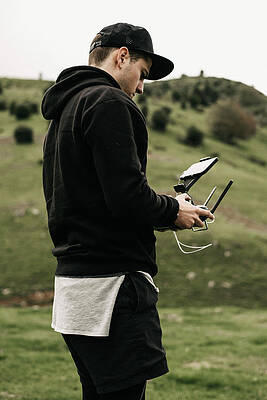 Wall Art - Photograph - Side View Of Man Holding Remote Control While Standing Against Mountain by Cavan Images
