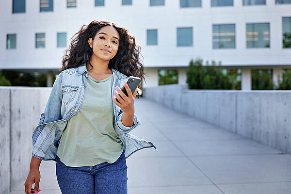 Wall Art - Photograph - Woman With Smart Phone Walking In Front Of Building by Cavan Images / Jack Jeffries