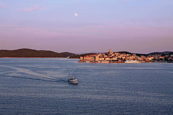 A fishing boat moves through the calm waters near a coastal town of Korcula, Croatia by Luigi Morbidelli
