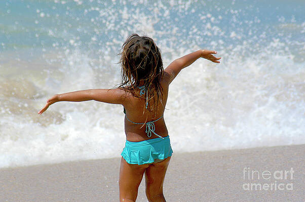 A young girl enjoying herself at the beach in the ocean spray. by Gunther Allen A young girl enjoying herself at the beach in the ocean spray. by Gunther Allen