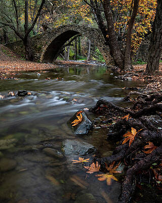 Wall Art - Photograph - Autumn landscape with river flowing below an ancient stoned bridge by Michalakis Ppalis