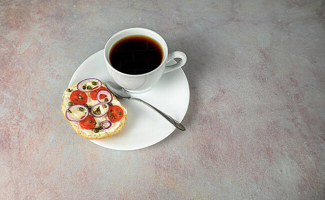 Wall Art - Photograph - Coffee and bagel on white on pink tinged countertop. by Mike Worley