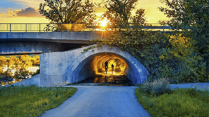 Digital Art - Cyclists Entering A Tunnel Located Under A Bridge At Sunset - Digital Painting by Nicko Prints