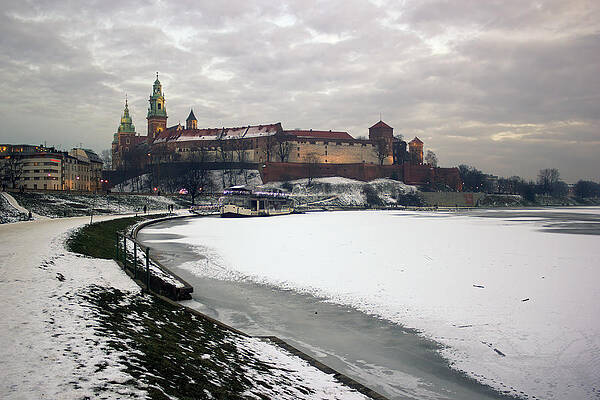 Wall Art - Photograph - Krakow, Poland -  Wide angle view of famous wawel castle covered with snow next to vistual river against dramatic clouds by Arpan Bhatia