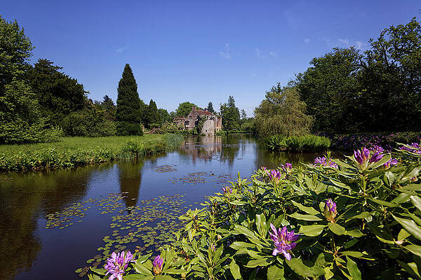  Photograph - Springtime and the moat with lilies and shrubs in flower surrounding Scotney Castle at La by John Gilham