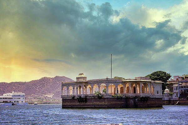 Wall Art - Photograph - Udaipur, India - Architecture built within Lake Pichola surrounded by hills against dramatic clouds in sunset by Arpan Bhatia