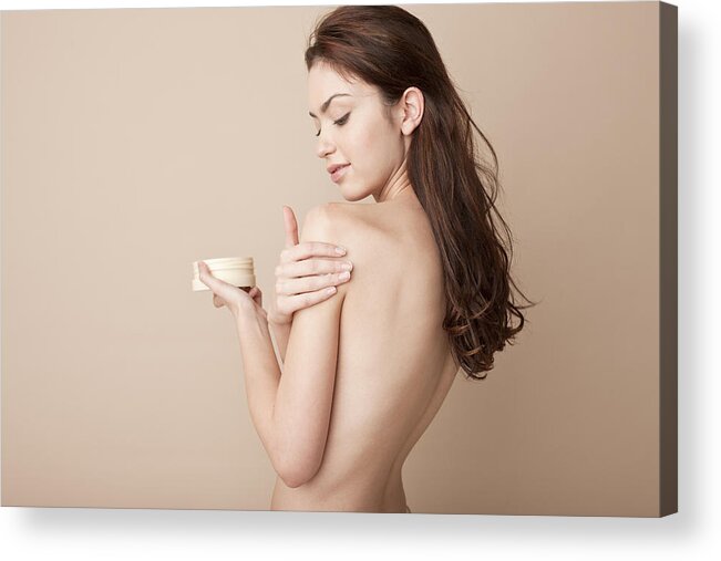 People Acrylic Print featuring the photograph A woman rubbing lotion on her naked arm by Unaemlag