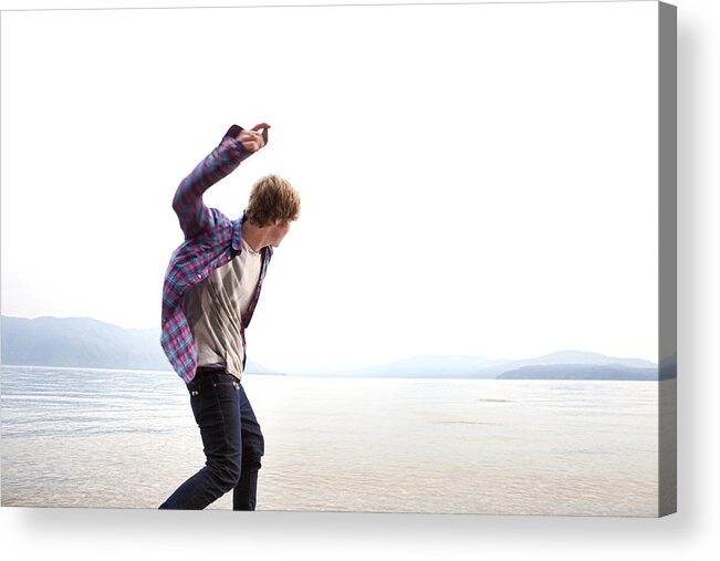 Wind Acrylic Print featuring the photograph Caucasian man skimming stones on lake by Ronnie Kaufman