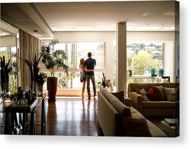 Heterosexual Couple Acrylic Print featuring the photograph Couple admiring the view from the living room of their house. by Capuski