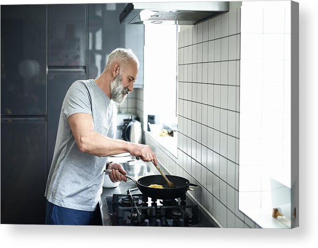 Cool Attitude Acrylic Print featuring the photograph Senior man with grey beard using frying pan in modern kitchen by 10'000 Hours
