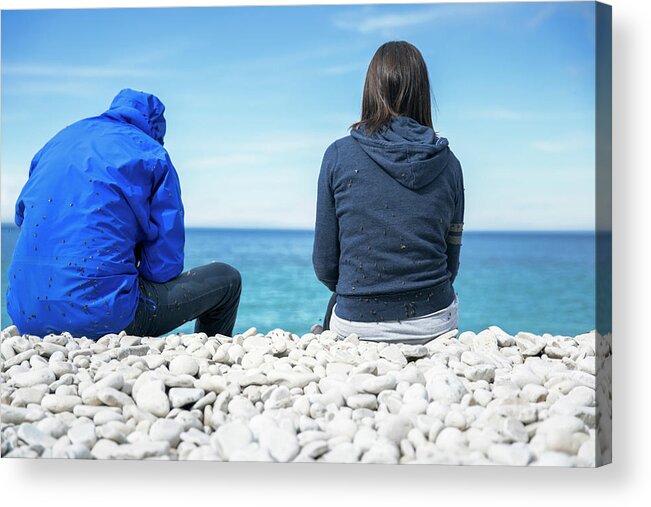 Young Women Acrylic Print featuring the photograph Two Persons Sitting On Rocky Beach by Marko Radovanovic