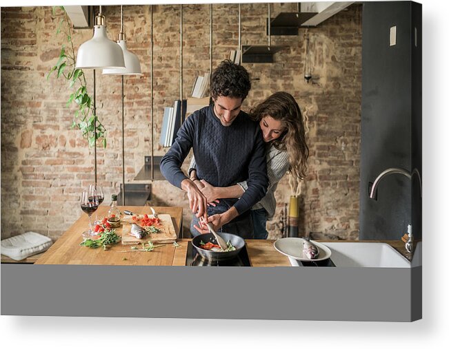 Young Men Acrylic Print featuring the photograph Young couple cooking fish cuisine at kitchen counter hob by Arno Images