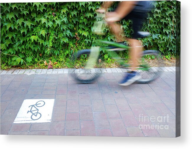 Action Acrylic Print featuring the photograph Motion blurred cyclists to show speed, driving along a bike lane by Joaquin Corbalan