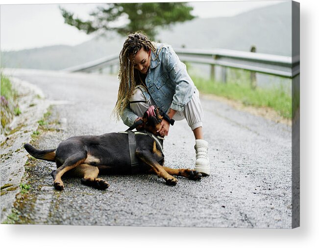 Young Acrylic Print featuring the photograph Young Woman With Blonde Braided Hair Wearing A Denim Jacket And White Jean Posing Next To Her Dog On A Rainy Day by Cavan Images