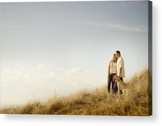 Tranquility Acrylic Print featuring the photograph Caucasian couple walking dog on grassy dunes by Chris Clor