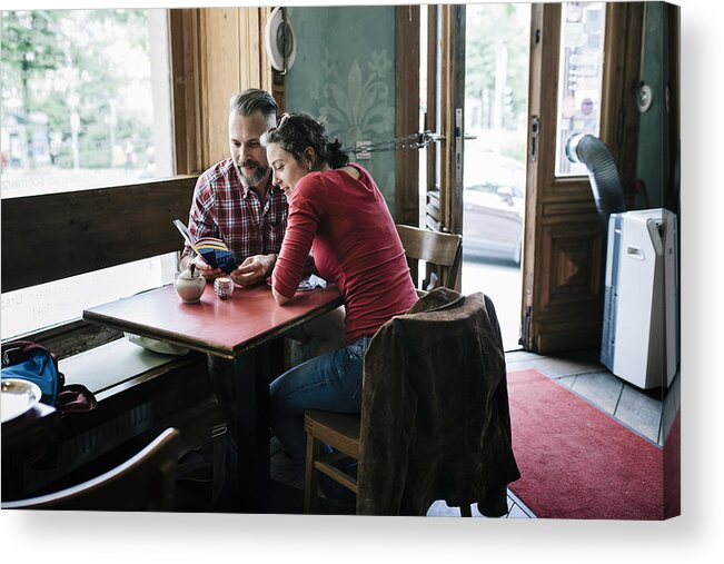 Heterosexual Couple Acrylic Print featuring the photograph Couple in Cafe reading Tour Guide by Hinterhaus Productions