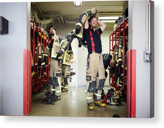 Expertise Acrylic Print featuring the photograph Firefighters wearing protective workwear in locker room while looking up at fire station by Maskot